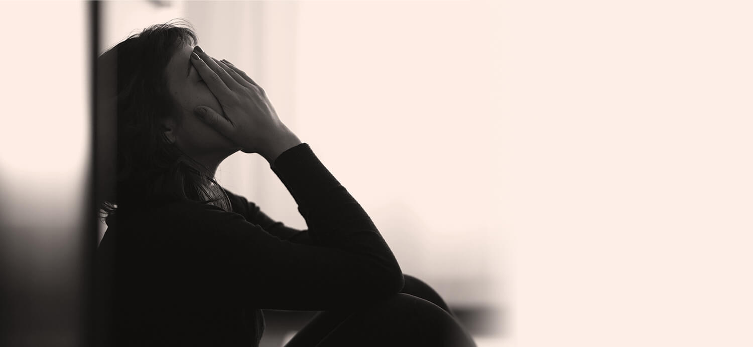 Girl sitting on floor looking sad with head in hands with white space